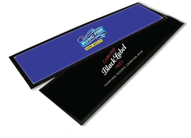 Two rectangular The Bar Runner mats are shown—one blue featuring a Flying Fish logo and one black with a Carling Black Label Beer logo.