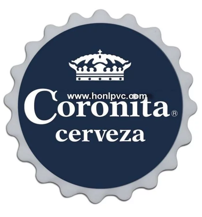The soft rubber coaster is a round sign resembling a bottle cap, featuring “Coronita cerveza” text and a crown logo on a dark blue background, with “www.honlpvc.com” displayed across the crown.