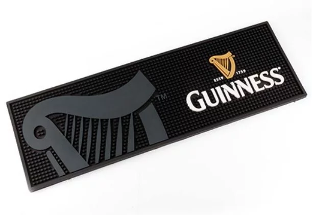 The Soft Rubber Bar Mat (Bar Rail) is a rectangular black mat with a gray harp on the left and the Guinness logo—gold harp and white text—on the right.