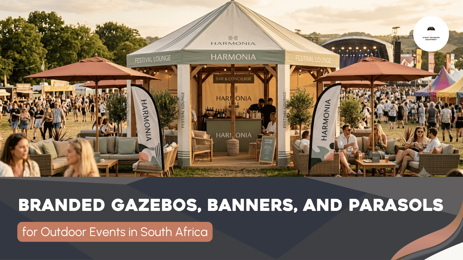Outdoor event with branded gazebos, banners, and parasols; people are gathered around seating areas on grass with a stage visible in the background.